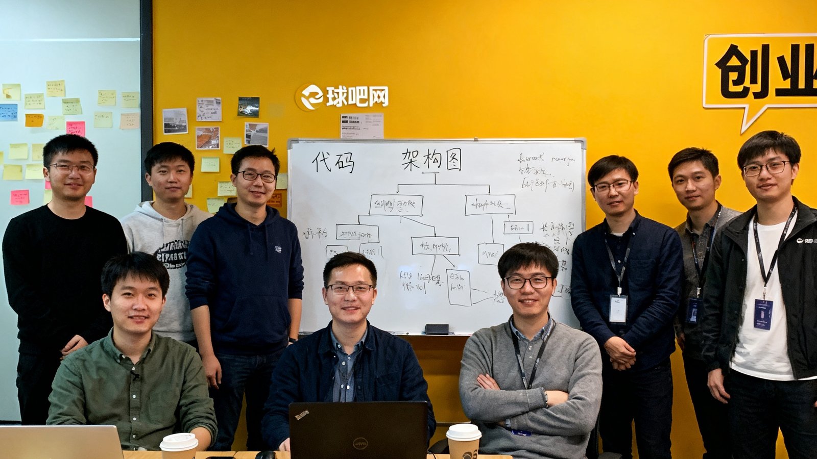 球吧网创始团队早期在杭州共享办公室的合影，白板上写满代码和架构图，充满创业氛围